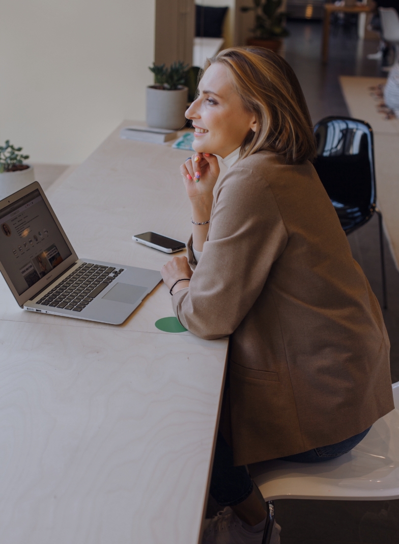 a smiling person looking at a laptop