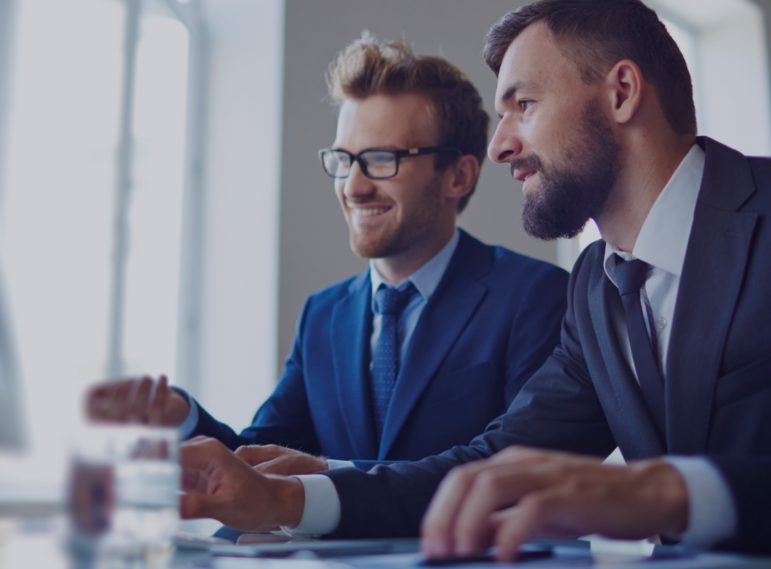 two people wearing suits at an office desk